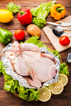 Whole Raw Chicken with ingredients for cooking. on wooden background