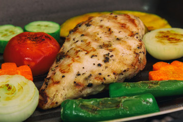 Grilled chicken breast on pan for barbecue with many vegetable. Close up concept of chicken breast barbecue for background. Roasted chicken breast for lunch or dinner. Delicious homemade barbecue.