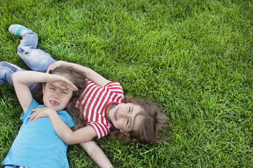 Fototapeta premium Lying on the grass in the park. Children in the park on a sunny summer day. View from above