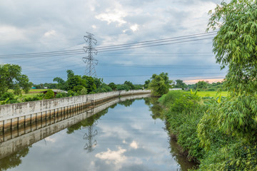 Landscape of  Flood protection wall with Wooden boats reflections in the water and trees on blue...