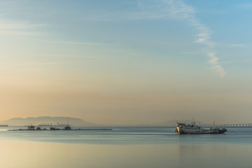 A fishing boat is mooring in the calm sea in a serene morning.