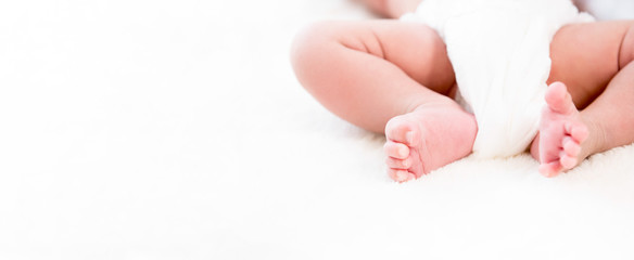 Baby legs and feet on white wool fluff sheet - web banner with copy space