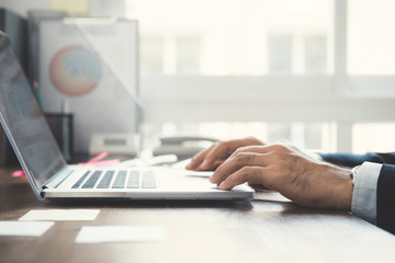 Hands of businessman using laptop computer at working desk