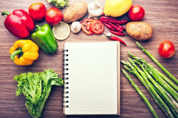 Fresh vegetables on the wooden background and paper for notes