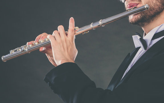 Elegantly dressed male musician playing flute