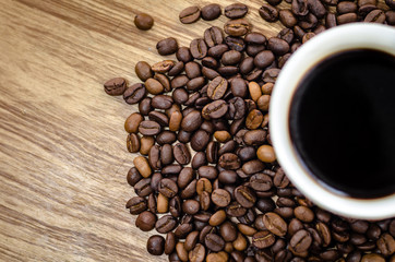 Coffee beans on wooden table with coffee mug.