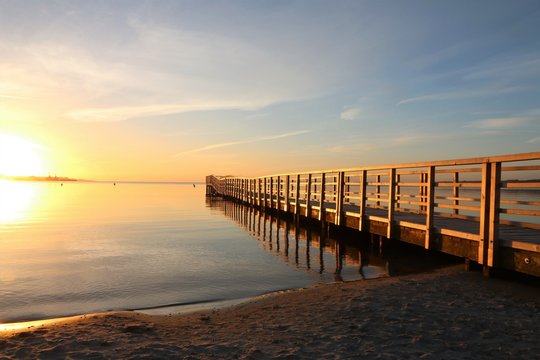 malerischer Sonnenaufgang an der Ostsee mit angestrahlter Seebrücke am Strand