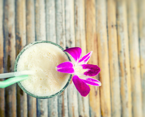 Cocktail decorated with orchid on a bamboo table. Vacation on the tropical sea concept