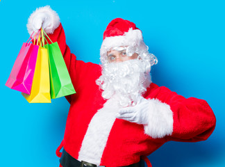 Funny Santa Claus have a fun with shopping bags on blue background