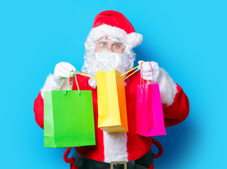 Funny Santa Claus have a fun with shopping bags on blue background