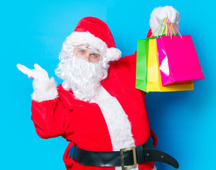 Funny Santa Claus have a fun with shopping bags on blue background
