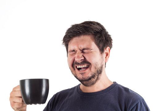 Portrait of Man drinks coffee from black mug at early morning. Yawn face man with open mouth