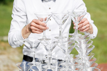 Waiter builds a pyramid of glasses for champagne