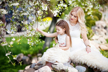 Pregnant mother and her small daughter in the summer gardenr. Family look portrait