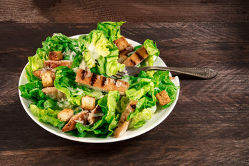 Chicken Caesar salad on rustic background with copyspace