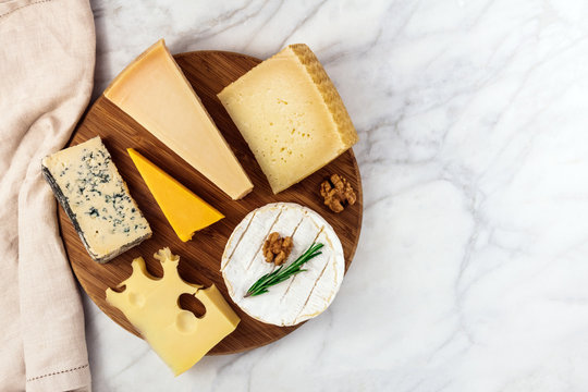 Selection of cheeses on white marble table with copyspace