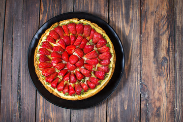 Cheesecake with strawberries, bio homemade strawberries from garden on wood background