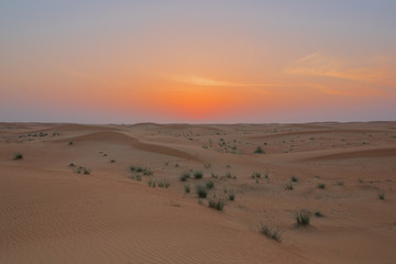 Fototapeta na wymiar Sky bursting in colors when the sun touches the horizon in the Dubai desert