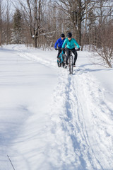 Fototapeta na wymiar Attractive couple riding fat bikes in the snow