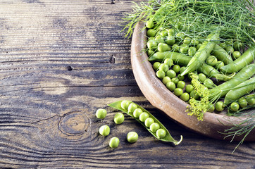 Fresh peas in a plate on a wooden background