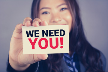 WE NEED YOU! message on the card shown by a businesswoman