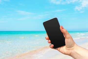 Beautiful woman's hand using smart phone at beach