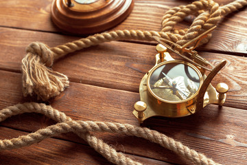 Compass and rope on wooden table. close up