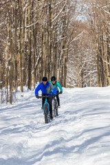 Attractive couple riding fat bikes in the snow