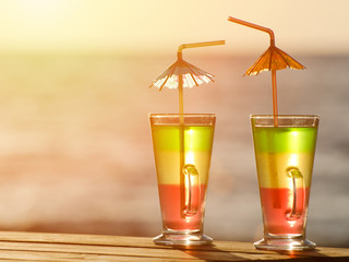 Two colorful cocktails in the sunset on the sea background, close up