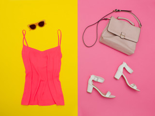 Pink top, handbag, white shoes and rose-colored glasses. Bright pink-yellow, background, close-up