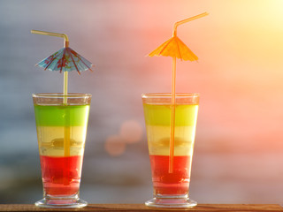Two glasses with colored cocktails close up on sea background, toning