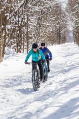 Fototapeta na wymiar Attractive couple riding fat bikes in the snow