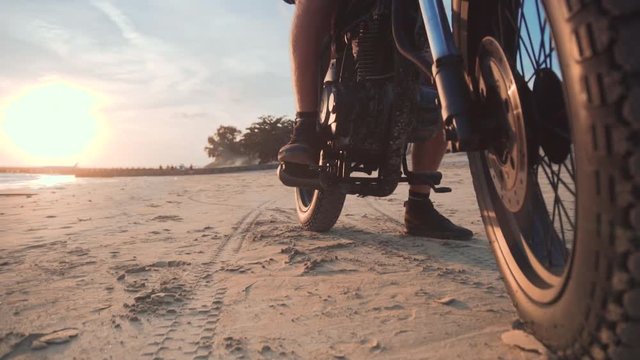 Close up dolly shot of motorcyclist and his motorbike on the road during sunset
