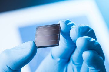 Scientist hold in hand small tile of new type efficient solar cell tile, solar technology research...