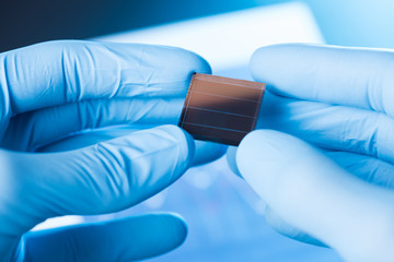 Scientist hold in hand small tile of new type efficient solar cell tile, solar panel technology research concept