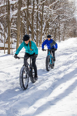 Attractive couple riding fat bikes in the snow