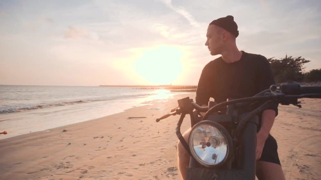 Dolly shot of motorcyclist and his motorbike on the road during sunset