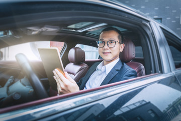Businessman sit in his car using digital tablet.