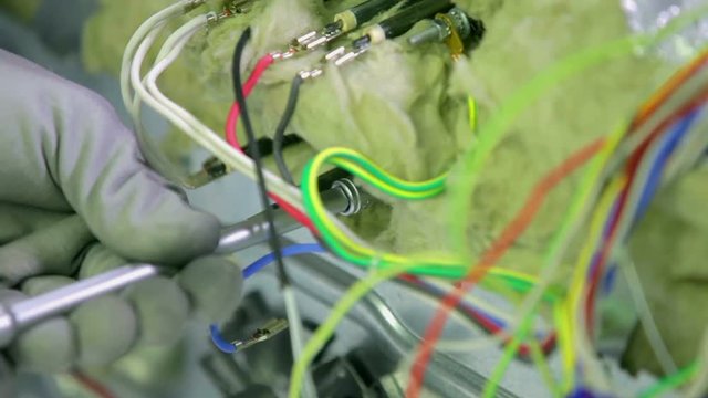 A man is trying to fix something on the device and he is using different tools. 