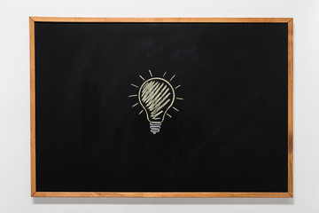 electric bulb drawn on black chalkboard in wooden frame