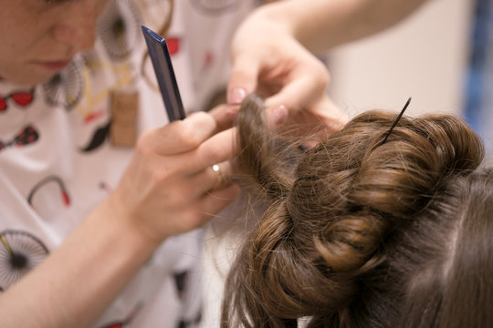 a hairdresser does a hairstyle for a girl in a hairdresser's 