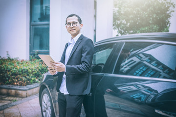 young businessman using digital tablet beside his car.