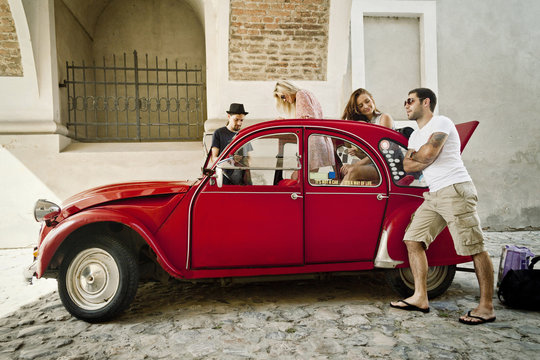 Group of friends preparing for road trip in a vintage car