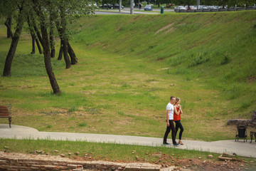 A loving couple strolls through the city park on a sunny summer day. Young boy and girl. Top view.