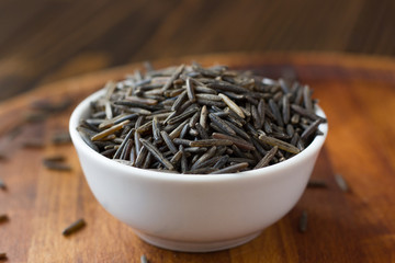 Black wild rice in ceramic bowl over wooden board
