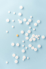 Top view of white pills with yellow tablet