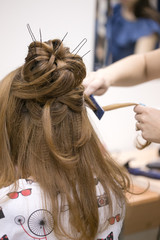 Fototapeta premium a hairdresser does a hairstyle for a girl in a hairdresser's 