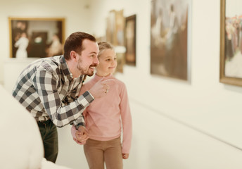positive father and daughter regarding paintings in museum