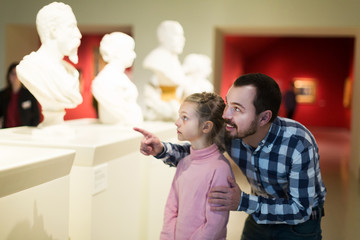 Father and daughter looking at classical statues