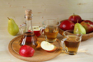 Apple cider and fruit on wooden background.